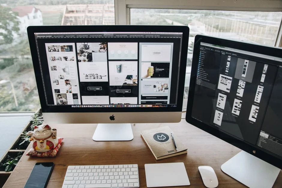 A top-down view of a minimalist workspace featuring a laptop and blank paper on a wooden table.